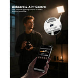 Person holding a camera with a smartphone displaying control app, surrounded by lighting equipment.