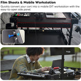 Film shoots and mobile workstation with cart and side panel, person using laptop outdoors.