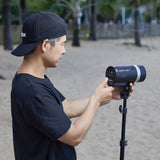 A photographer inserting a battery into the back of a  Godox AD300proII Portable Battery Flash
