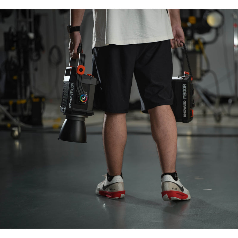 a Gaffer carrying an M300R in one hand and its controller box in the other to show portability