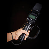 A person handholding a PB1000 battery grip with a speedlite mounted on top of it 