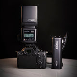 A person handholding a PB1000 battery grip with a speedlite mounted on top of it 