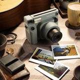 Instax Wide 400 Instant Camera - Green on a wooden table  surrounded by photo prints