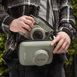 Person holding a green Instax Wide400 camera and case against a blurred green background