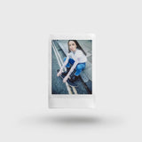 An Instax photo of a person sitting on a bench with a white border