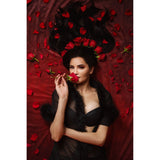 Woman holding a red rose amidst red petals and black feathers on a 2x3 Dark Red Wine Colour Abstract Weave Pattern Texture Studio Photography Background from Kate Backdrops