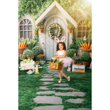 A young girl in bunny ears, standing in front of an Easter House Bunny Garden Carrots Backdrop with Easter decorations.