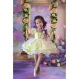 Young girl in a yellow dress sitting on a swing with floral decorations in front of the Sweep Fine Art Flower Gold Frame Purple Curtain Backdrop