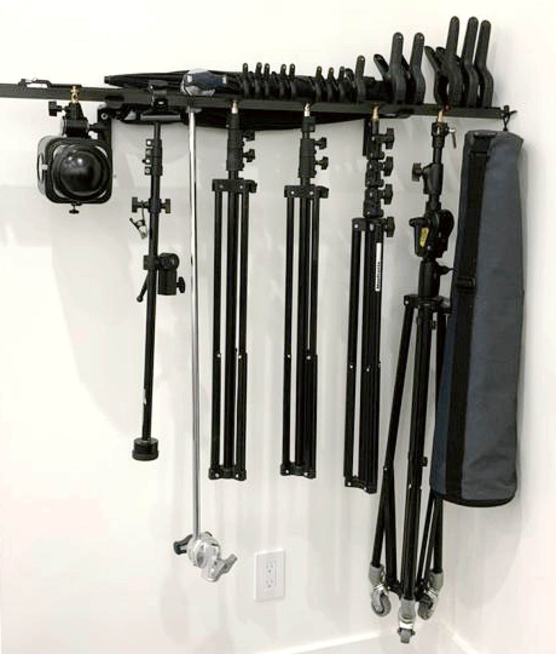 the PiXAPRO Heavy-Duty Wall-Mounted Stand Rack being used to hold a number of light stands, lights and accessories