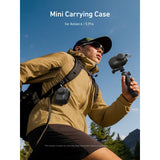  Hiker holding a TELESIN mini carrying case on a camera grip, with another case clipped to a backpack strap.