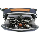 An open VEO CITY CB29 6 Litre Cross Body Camera Bag. The bag is organised with various camera accessories, including a tripod head, lens pieces, and a brown leather strap.