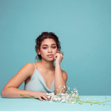 Woman in a light blue dress with flowers on a teal background